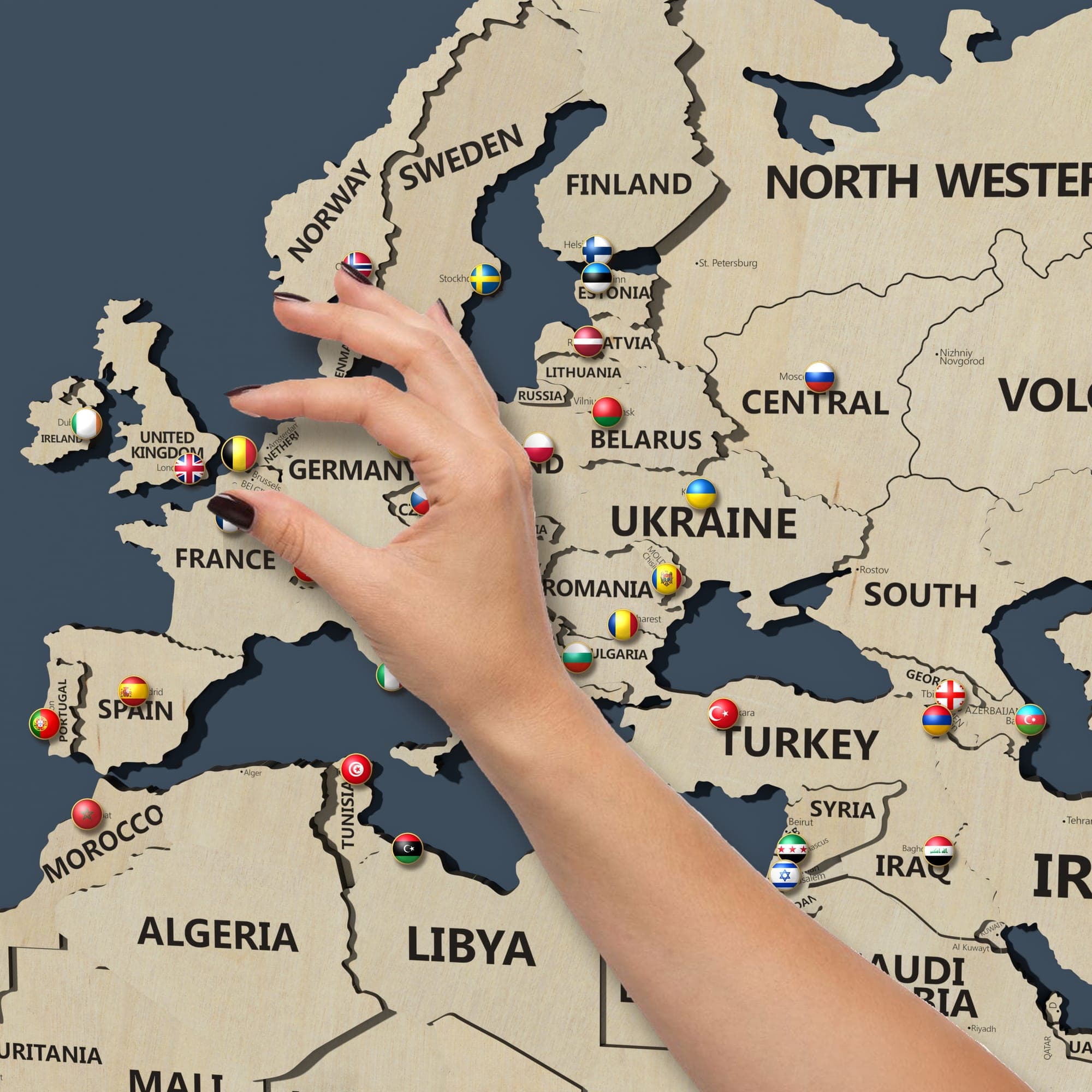 A hand placing a pin in Europe on the map in birch