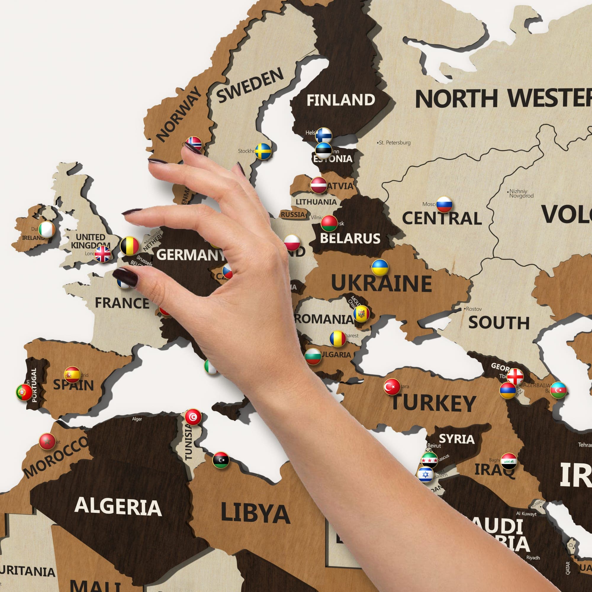 A hand placing a pin in Europe on the map in birch, teak and walnut