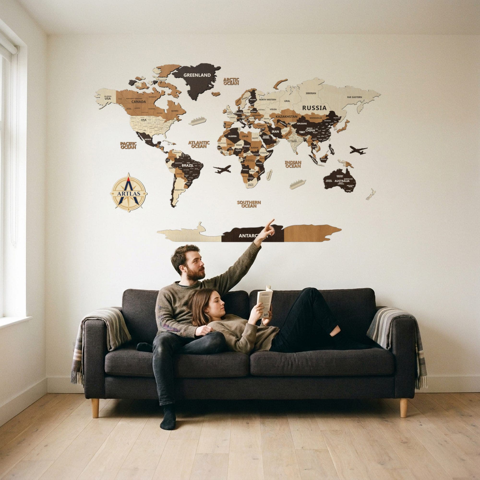 Two people on a sofa beneath the map in birch, teak and walnut