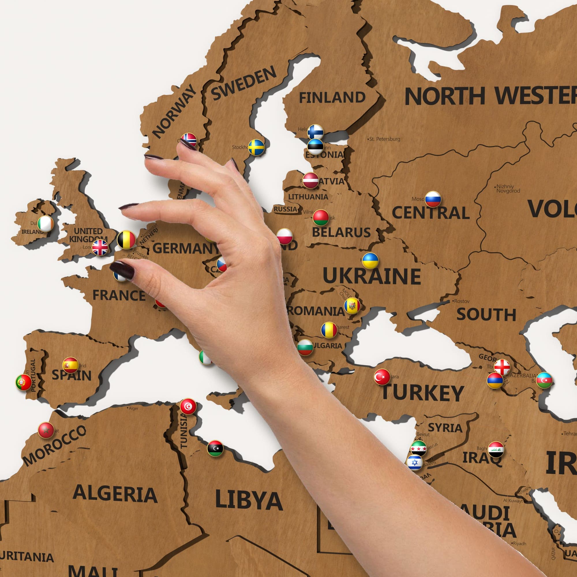 A hand placing a pin in Europe on the map in teak