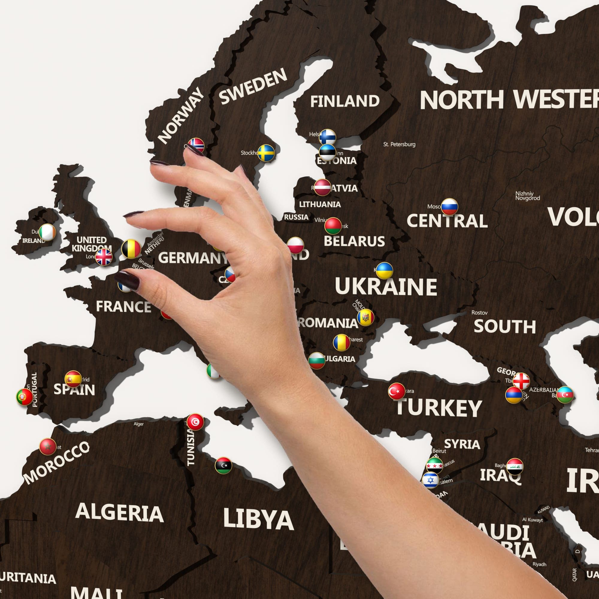 A hand placing a pin in Europe on the map in walnut